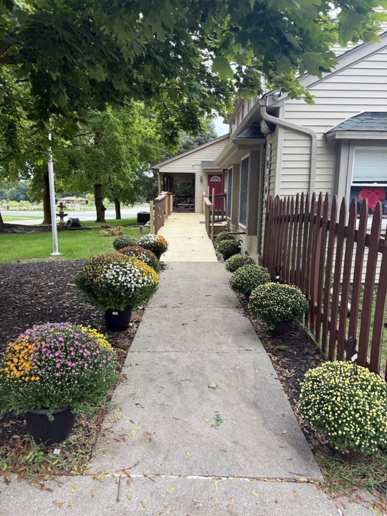 Sunny Pointe Child Care Center on Fry Road in Northville, MI — tree-shaded entrance walkway with fall mums