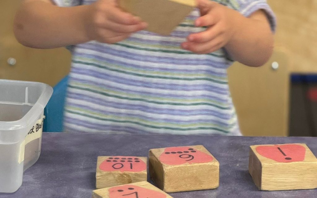 Preschooler learning numbers with wooden blocks at Sunny Pointe