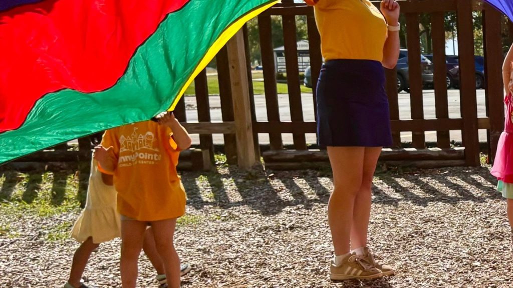Kids playing parachute games outside at Sunny Pointe Child Care Center in Northville